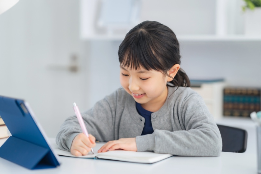 タブレットでアプリをしながら勉強する小学生