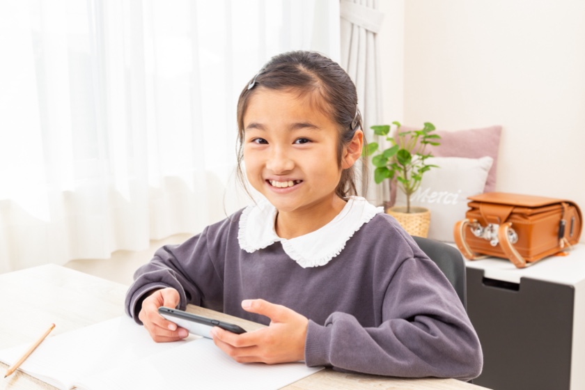 スマホでアプリをしながら勉強する小学生